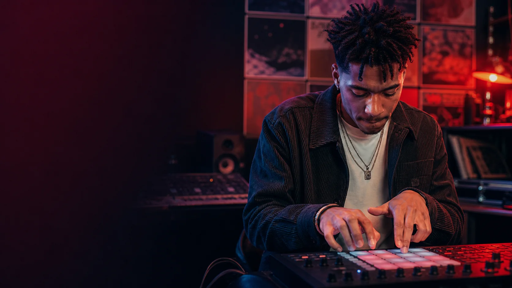 Beatmaker finger-drumming on a pad controller in a colorful studio