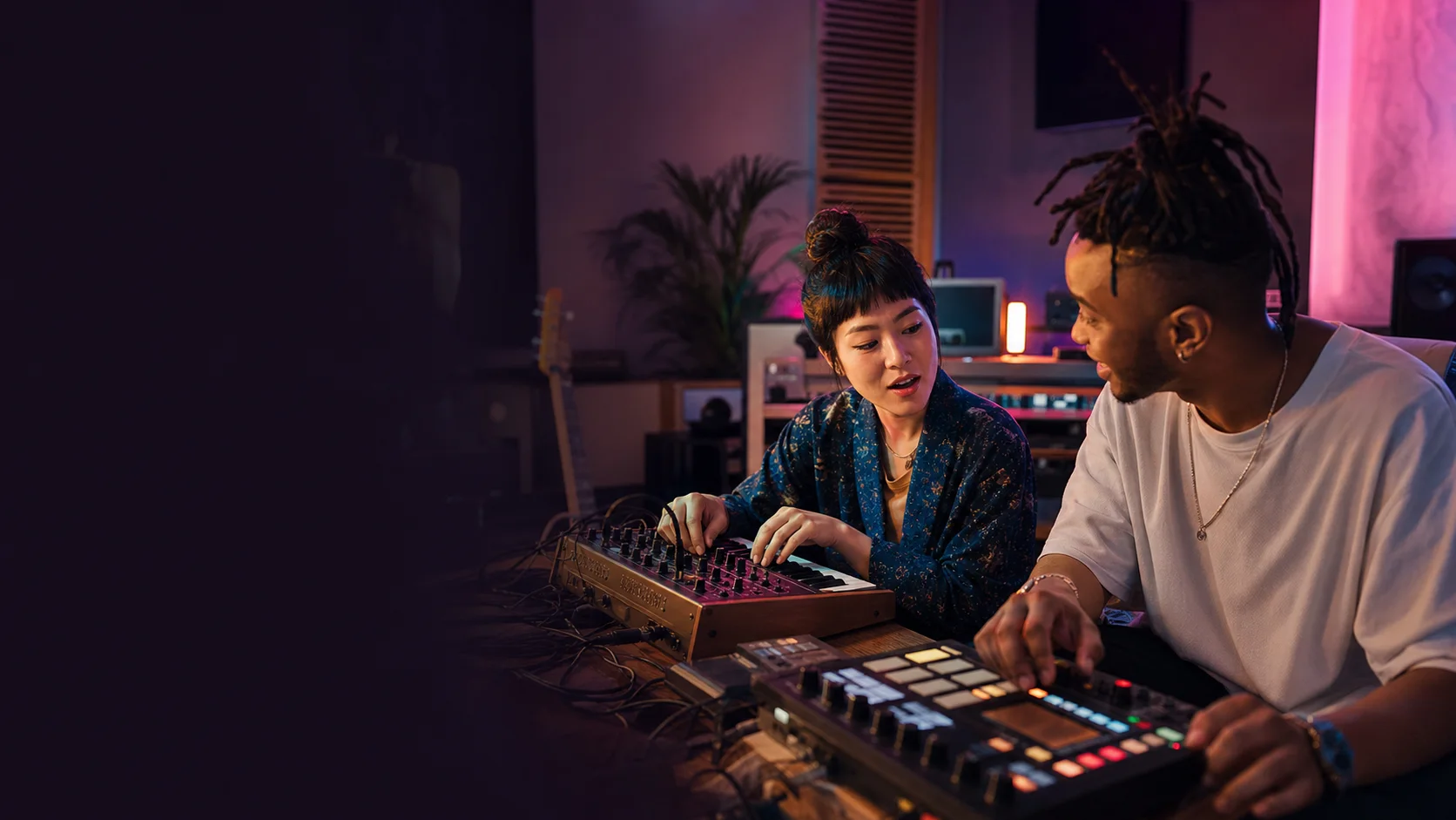 Two music producers combining sounds at a synthesizer and sampler
